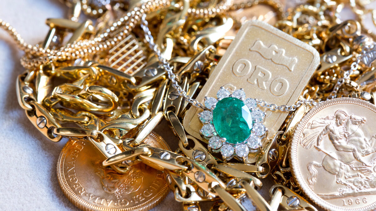 Assorted estate gold jewelry including chains, a green gem pendant, and gold coins, available at Gold Drop in San Rafael.