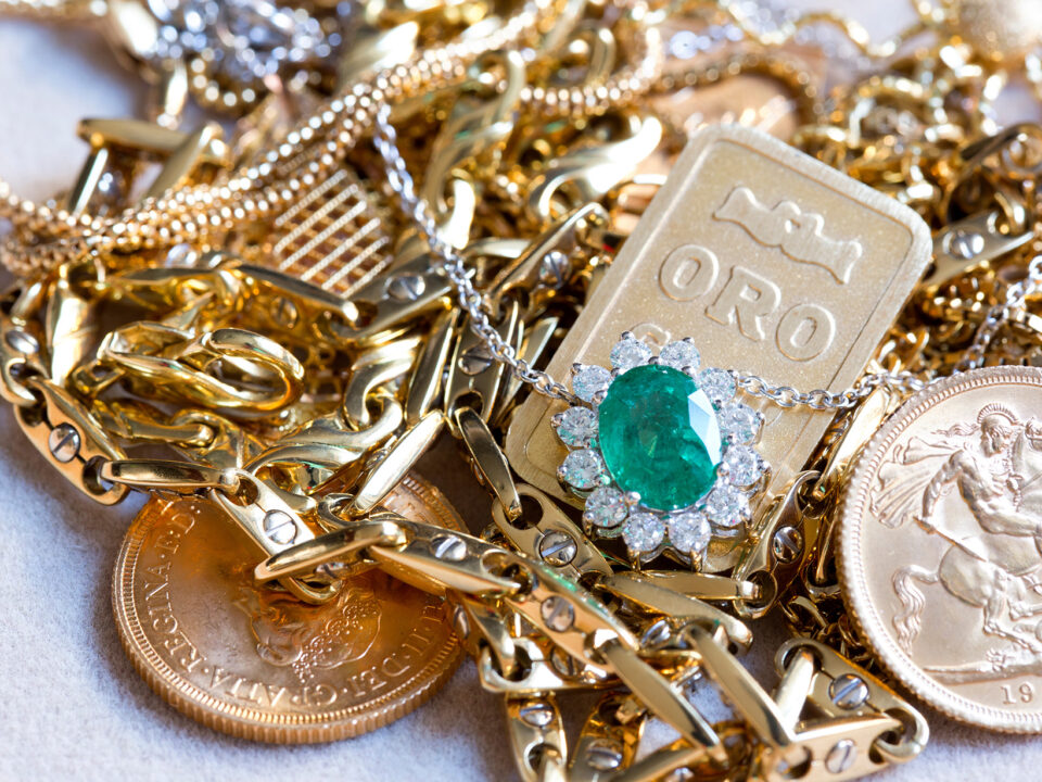 Assorted estate gold jewelry including chains, a green gem pendant, and gold coins, available at Gold Drop in San Rafael.