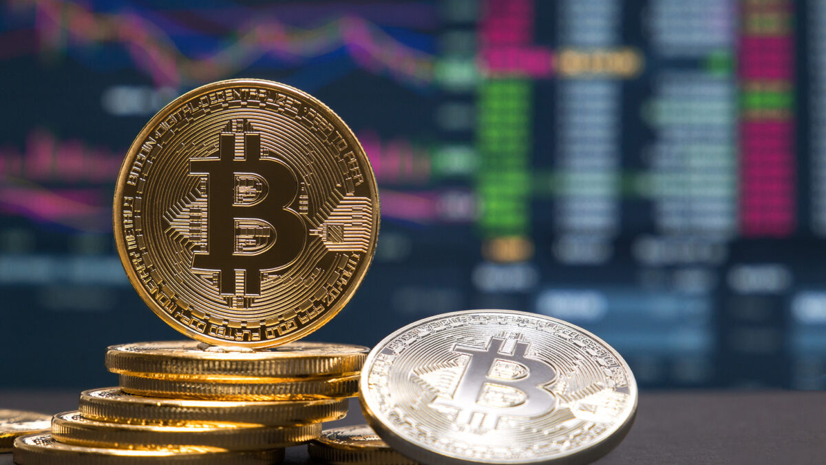 Gold and Bitcoin coins with financial charts in the background