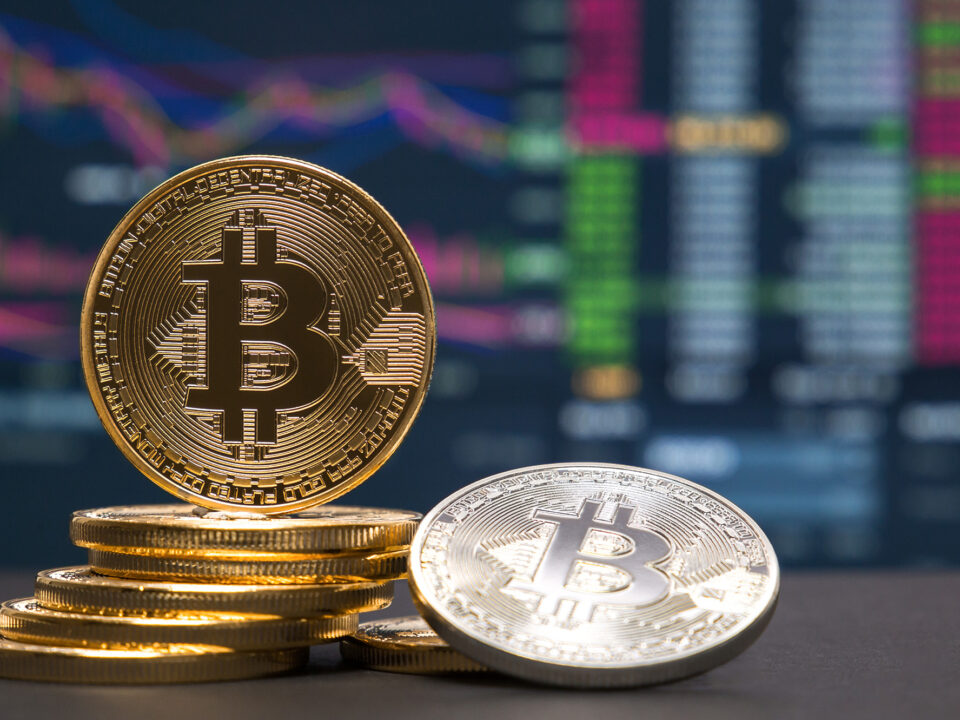 Gold and Bitcoin coins with financial charts in the background